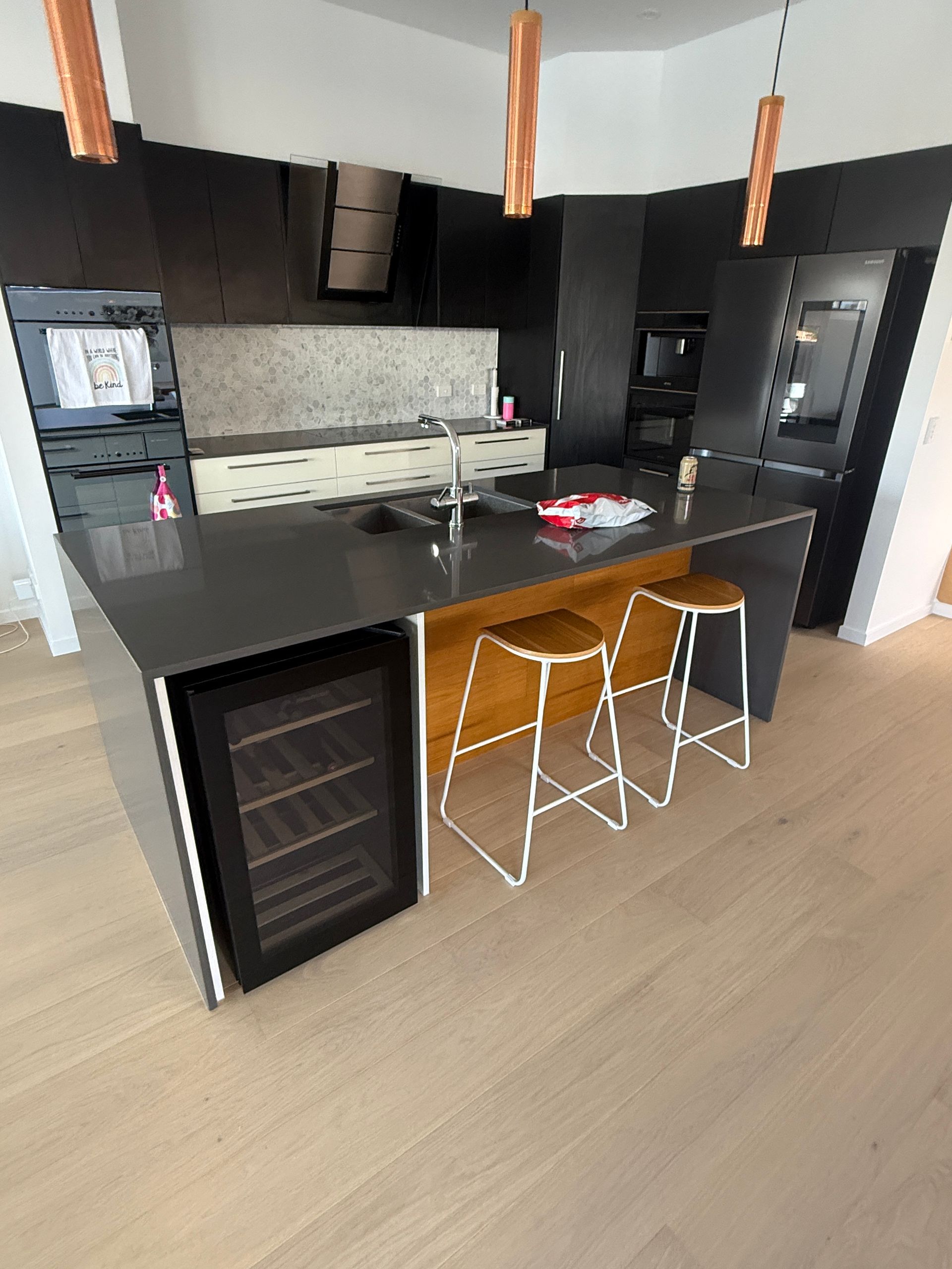 Modern Kitchen with Black Cabinets, Island, Two Stools, and Built In Wine Cooler — JPR Concepts in Burleigh Heads, QLD