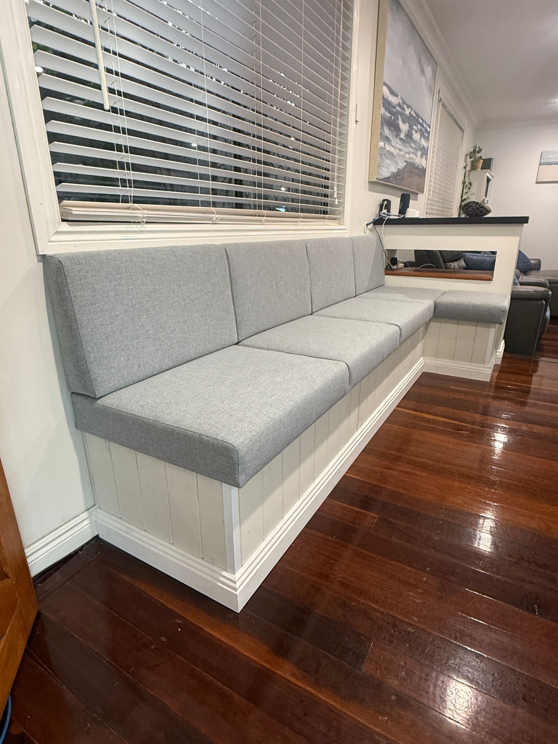 Gray Upholstered Bench Under Window Blinds in A Bright Room with Dark Hardwood Floors — JPR Concepts in Burleigh Heads, QLD