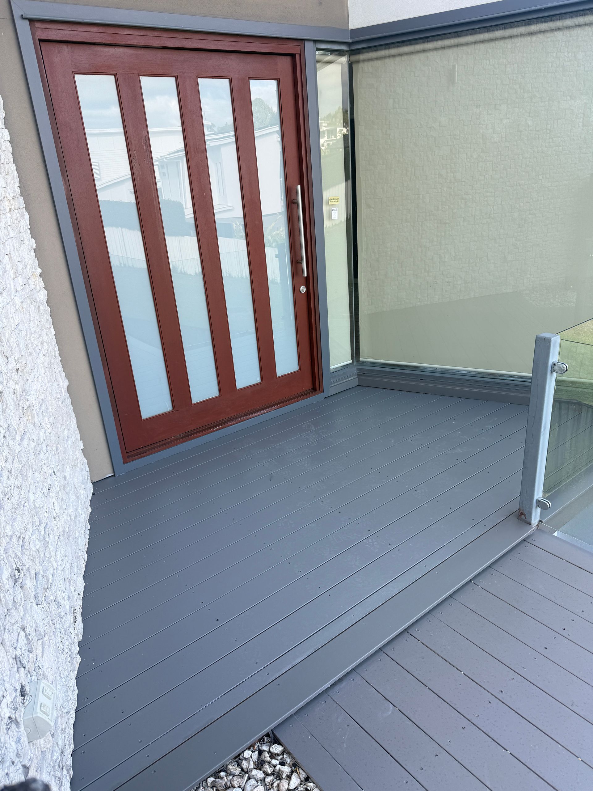 Small Outdoor Deck with Gray Flooring and A Brown Door with Frosted Glass Panels — JPR Concepts in Burleigh Heads, QLD
