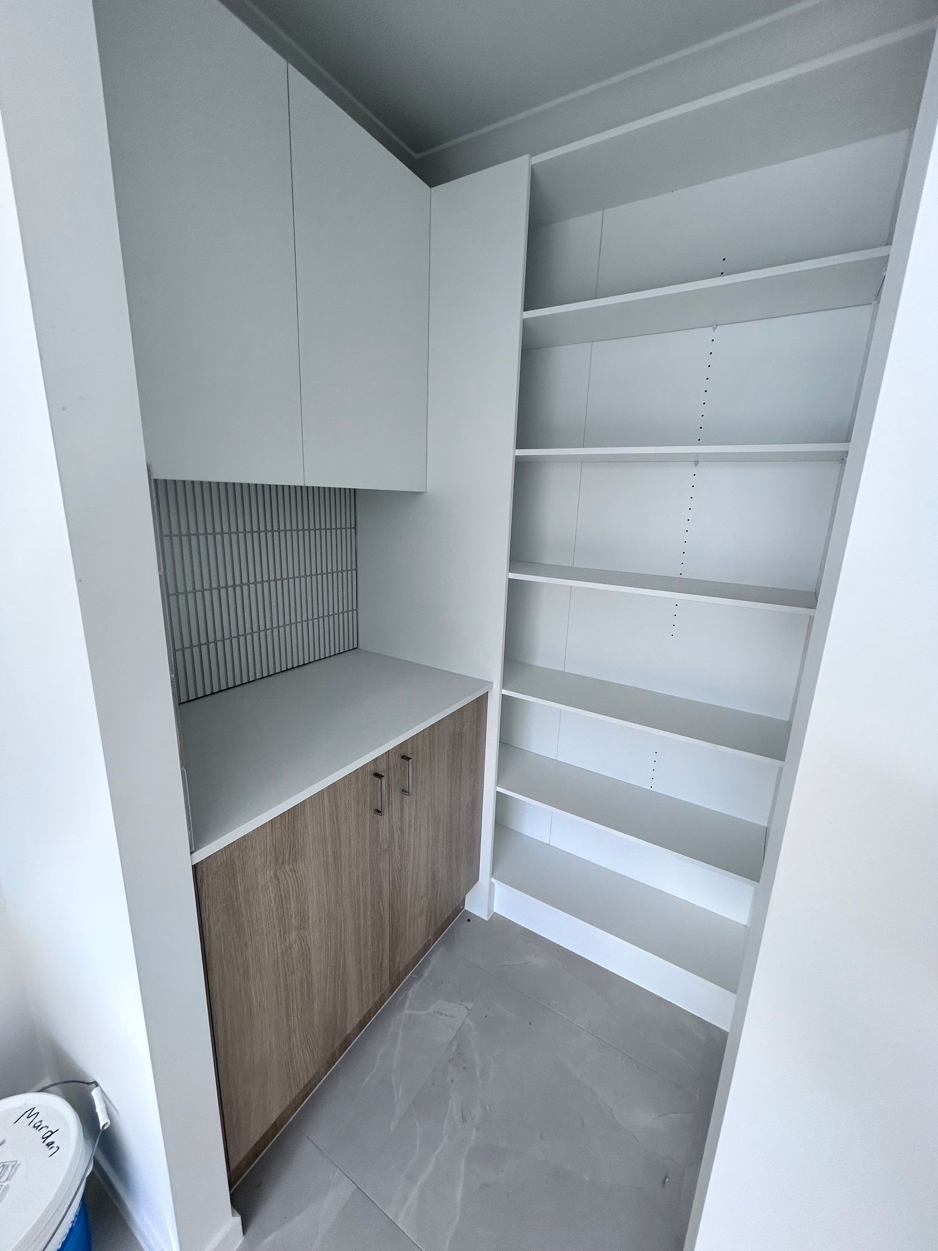 Built In White Shelves and Wood Cabinet in A Small Closet Nook with Gray Tile Floor — JPR Concepts in Burleigh Heads, QLD