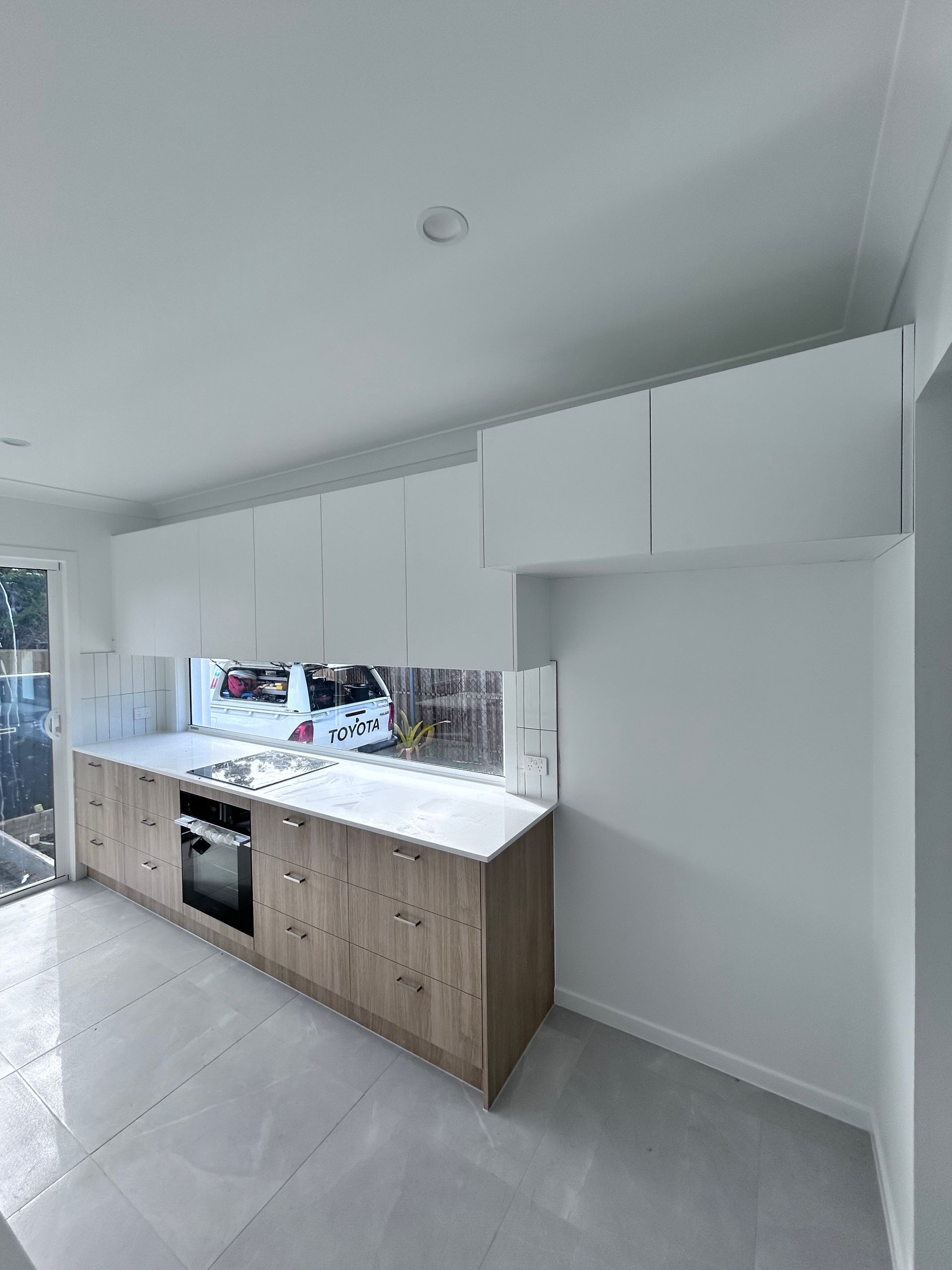 Modern White Kitchen with Wood Cabinets, Marble Look Counters, and A Large Window — JPR Concepts in Burleigh Heads, QLD