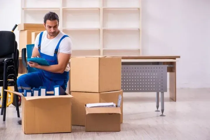 Moving specialist checking an inventory list in a room.
