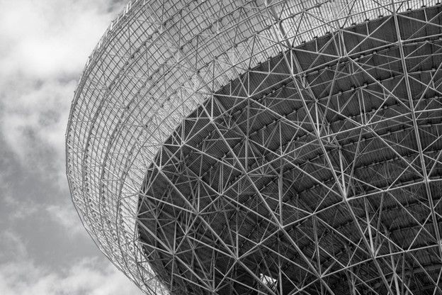 A black and white photo of a large metal structure against a cloudy sky.