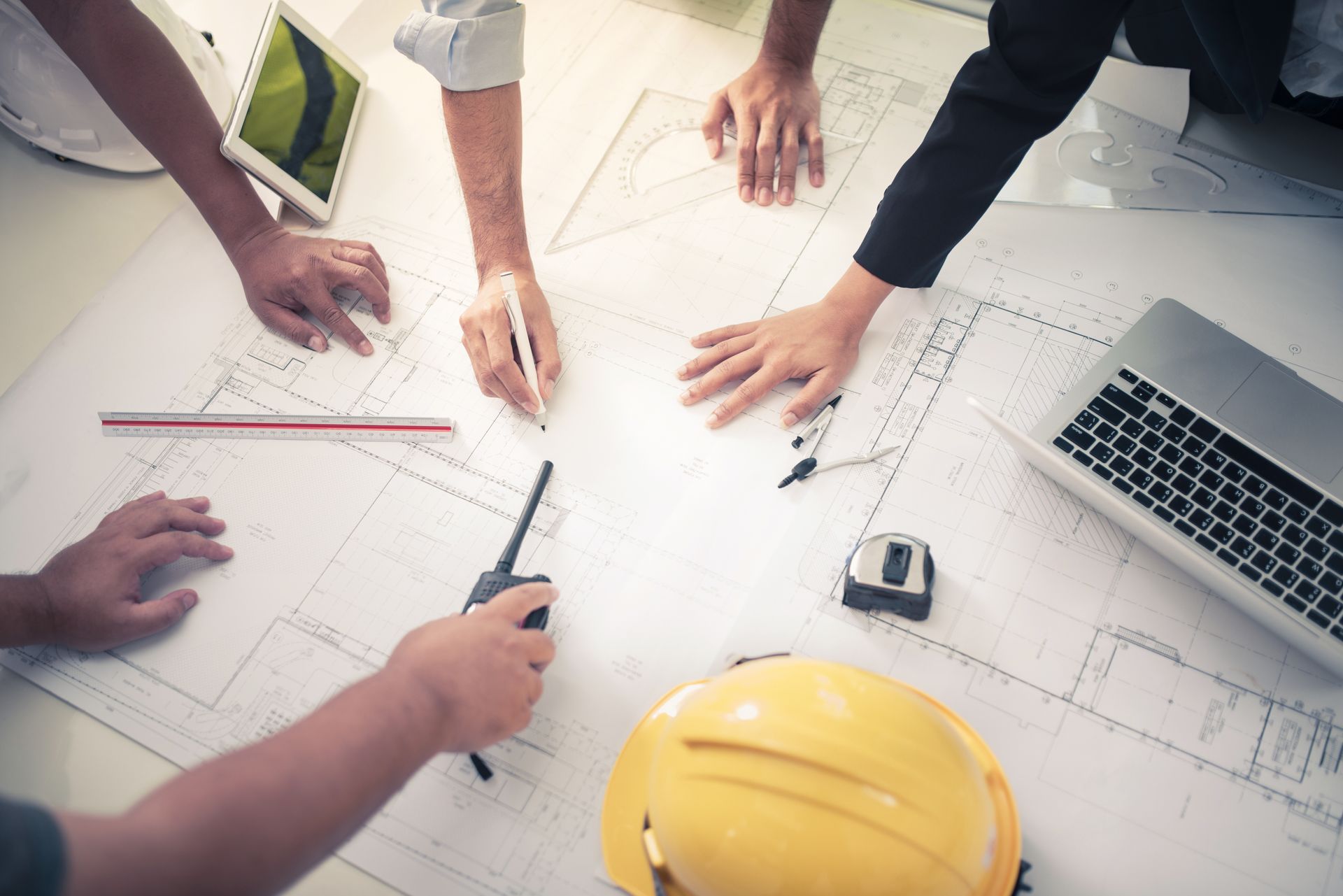 A group of people are sitting around a table looking at blueprints.