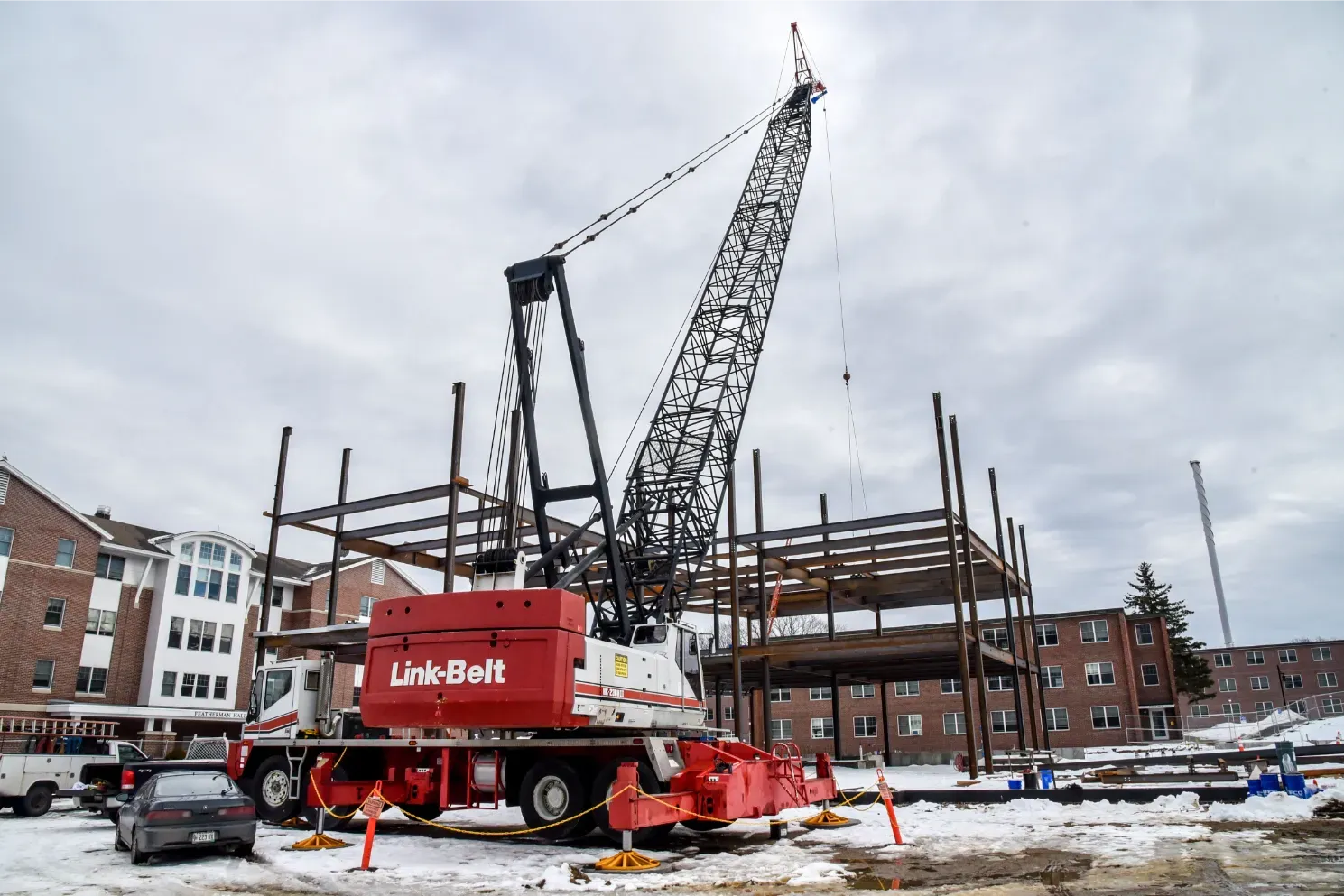Red Liebherr crane beside a partly built brick structure at a snowy construction site