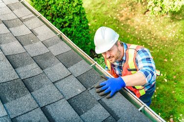 A man is fixing a gutter on a roof.