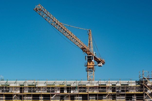 A construction crane is sitting on top of a building under construction.