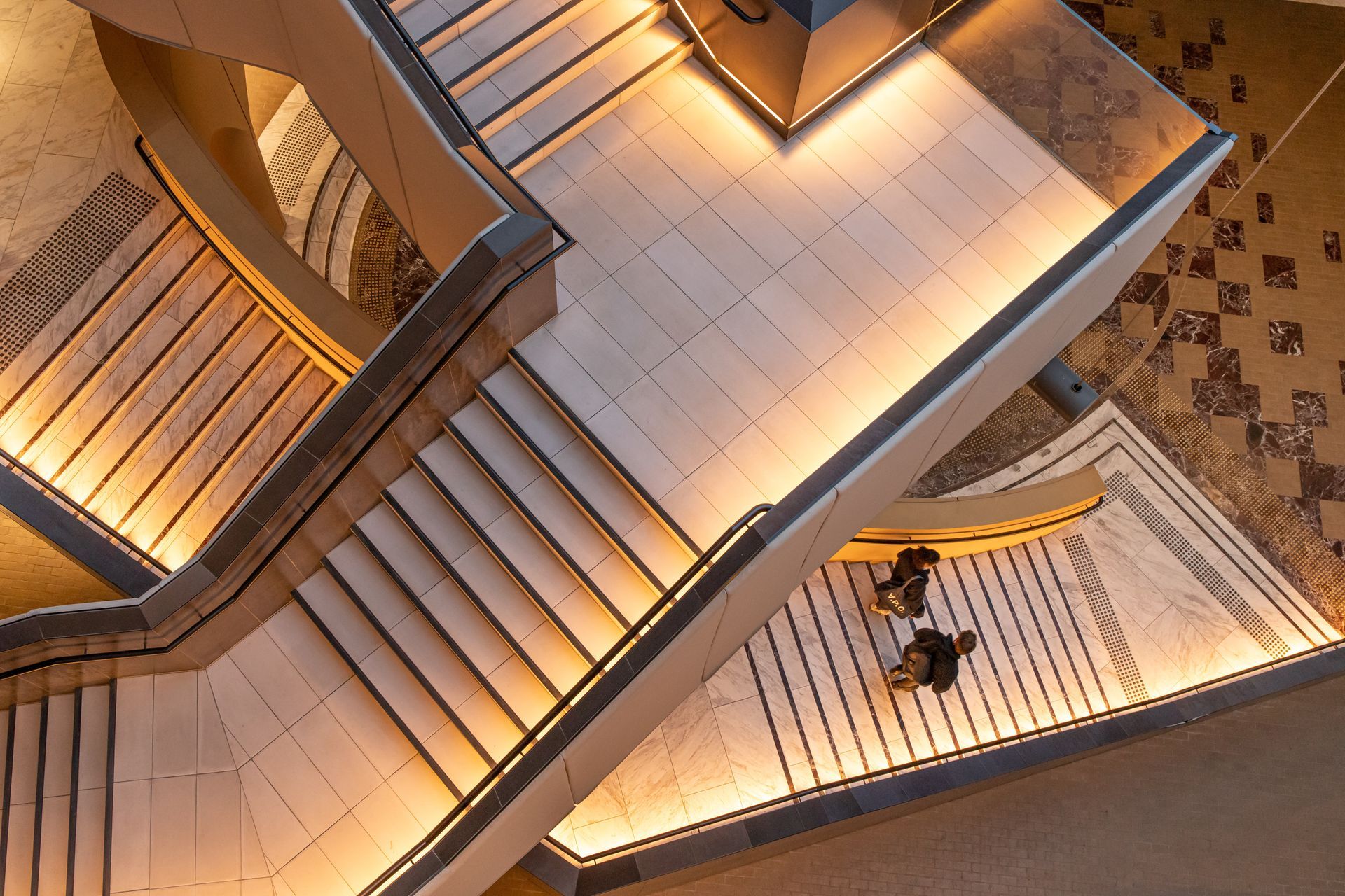 A couple of people are sitting on a set of stairs in a building.