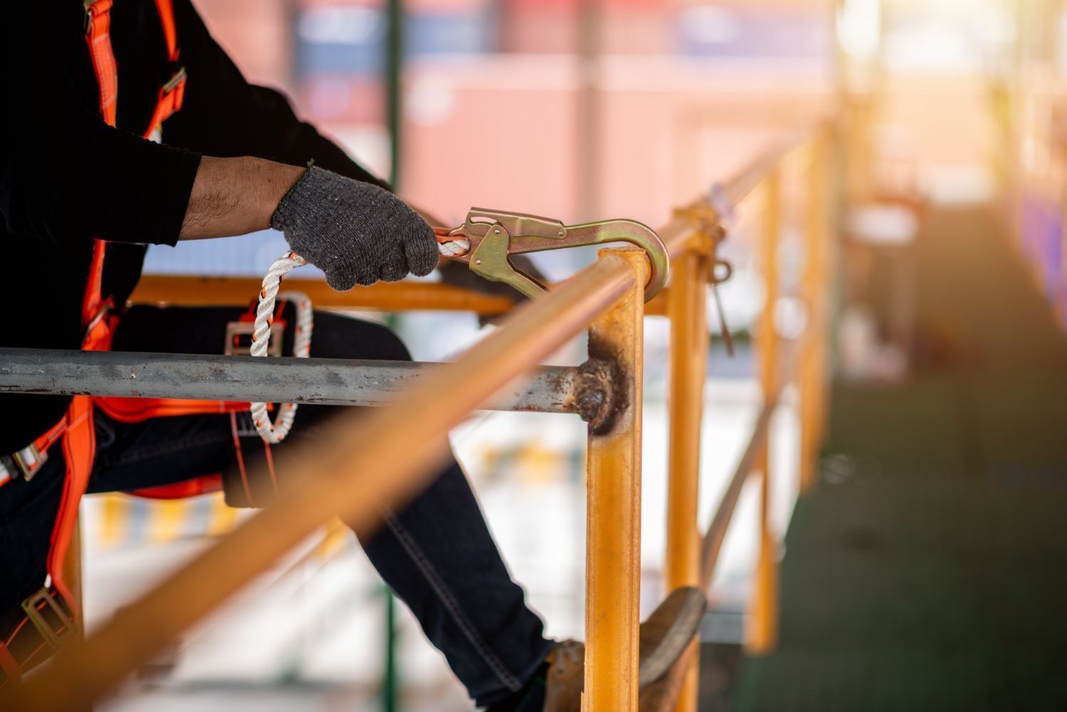 A man is sitting on a railing wearing a safety harness.