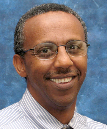 Man with glasses, smiling, wearing a striped shirt.