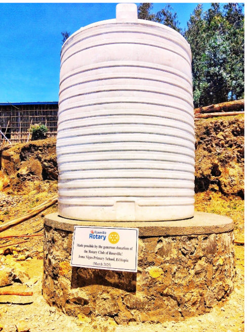 White water tank on a stone base, with a sign indicating it was a gift.