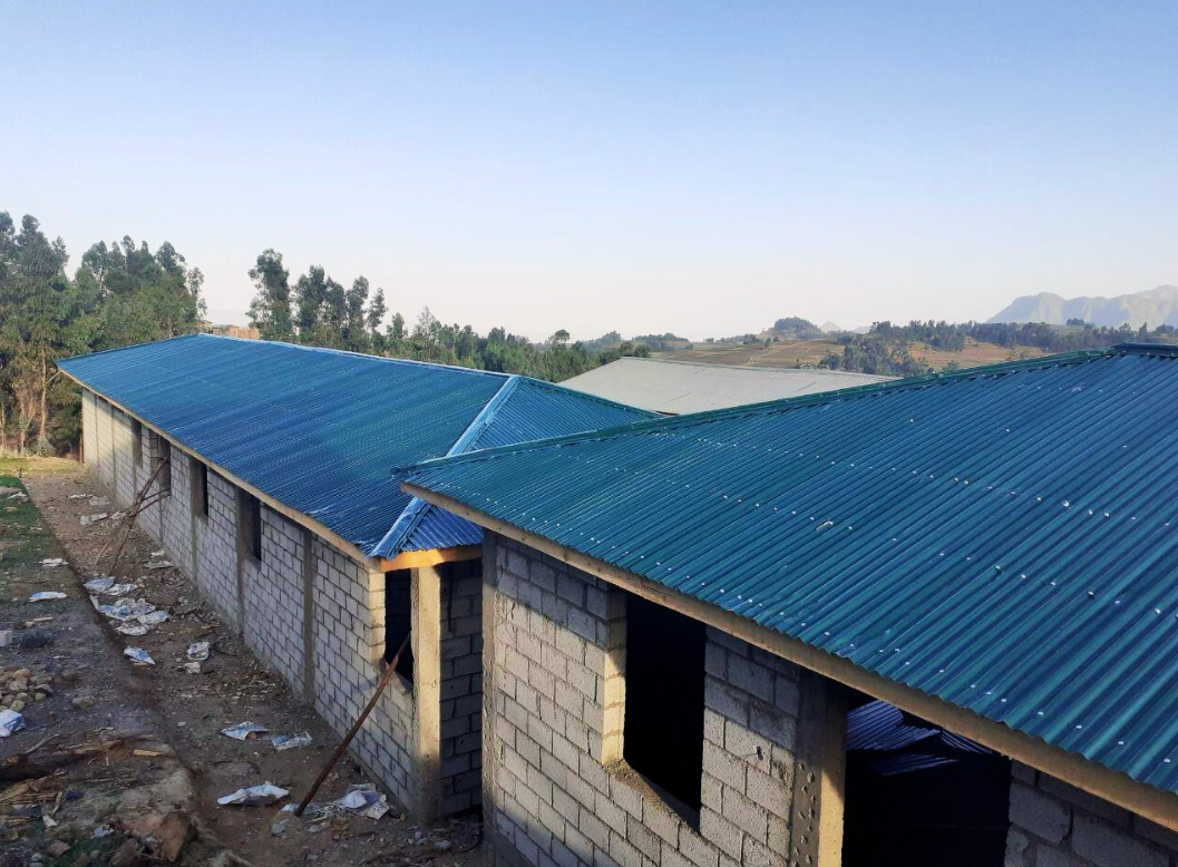Buildings with blue corrugated metal roofs under a light blue sky.