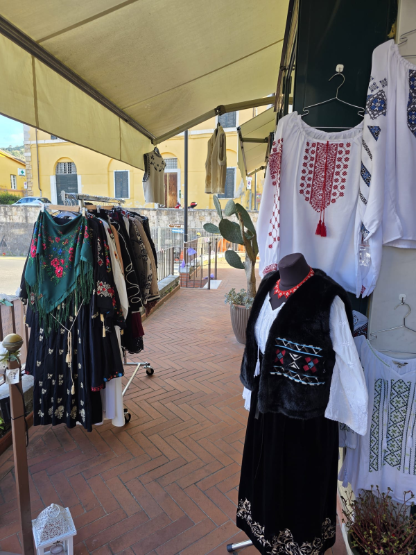 Esposizione di abiti in un negozio all'aperto. Camicette, abiti e giacche tradizionali ricamati su espositori e manichini.