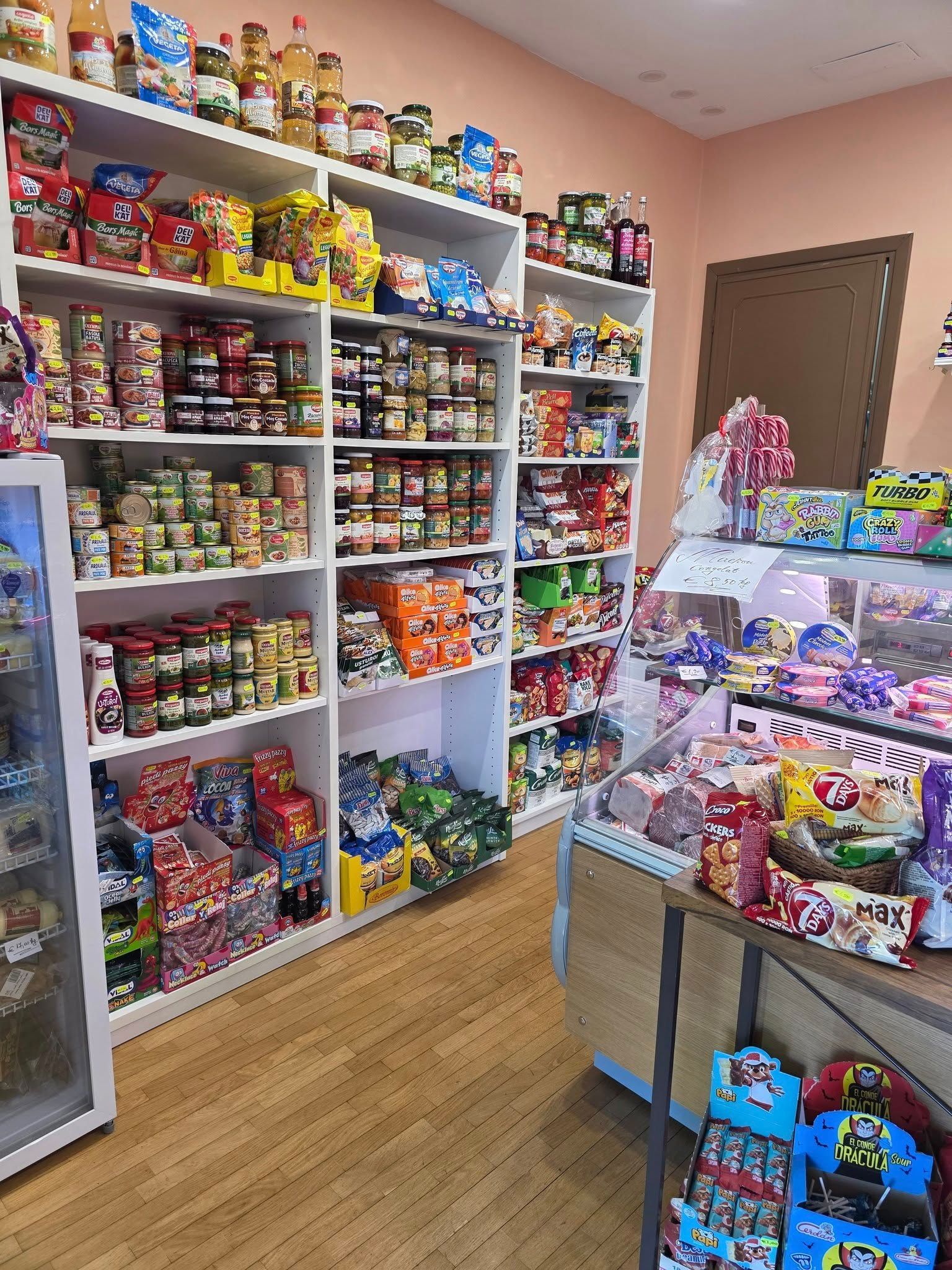 Scaffali pieni di prodotti alimentari confezionati in un piccolo negozio, tra cui caramelle e prodotti in scatola.