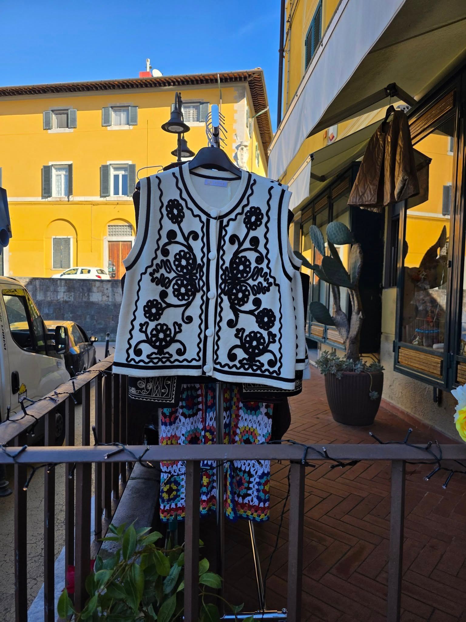 Gilet ricamato bianco e nero esposto fuori da un negozio in una giornata di sole.