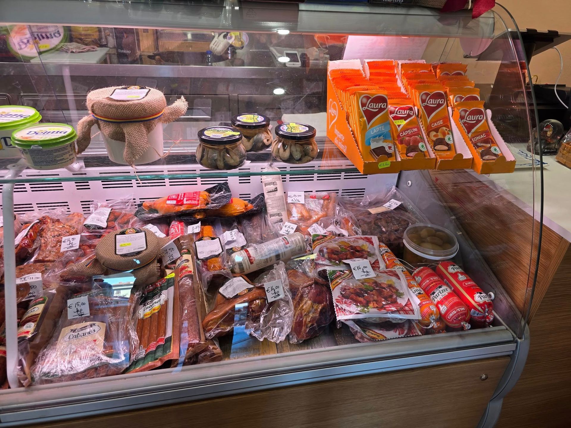 Vetrina gastronomia con vari tipi di carni confezionate, formaggi e altri cibi preparati.