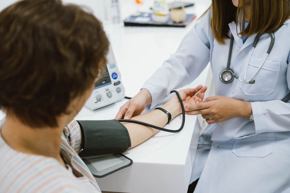 Doctor Checking a Patient Blood Pressure with A Cuff in A Clinic Room — Rainbow Beach General Practice in Rainbow Beach, QLD