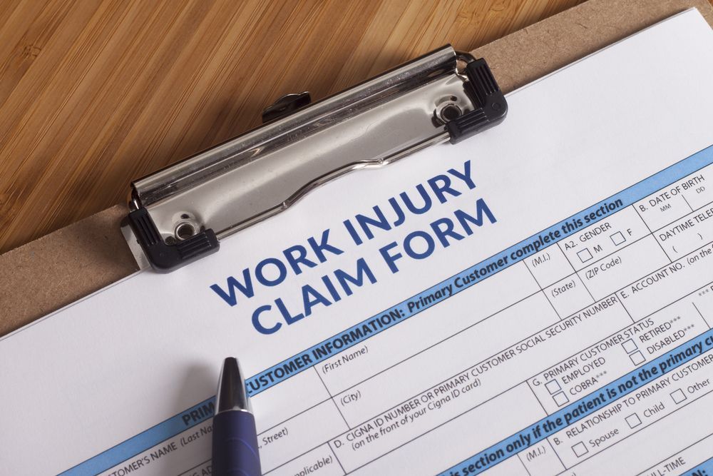 Work Injury Claim Form on A Clipboard with A Pen on A Desk — Rainbow Beach General Practice in Rainbow Beach, QLD