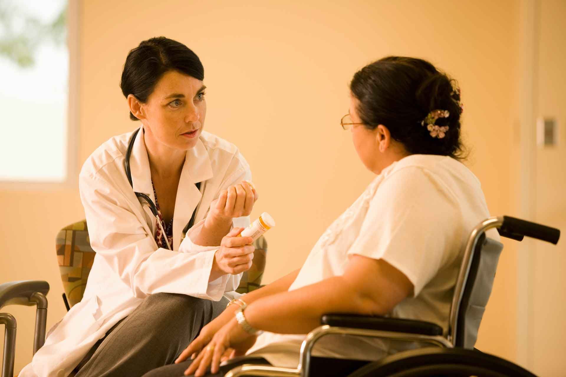 Healthcare Worker Talking Beside a Wheelchair in A Hospital Corridor — Rainbow Beach General Practice in Rainbow Beach, QLD