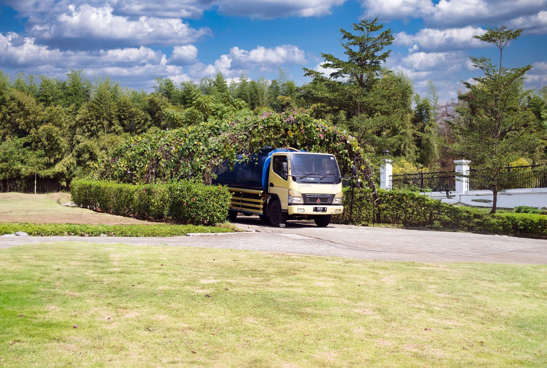Dump truck delivering a large pile of mulch to a residential driveway