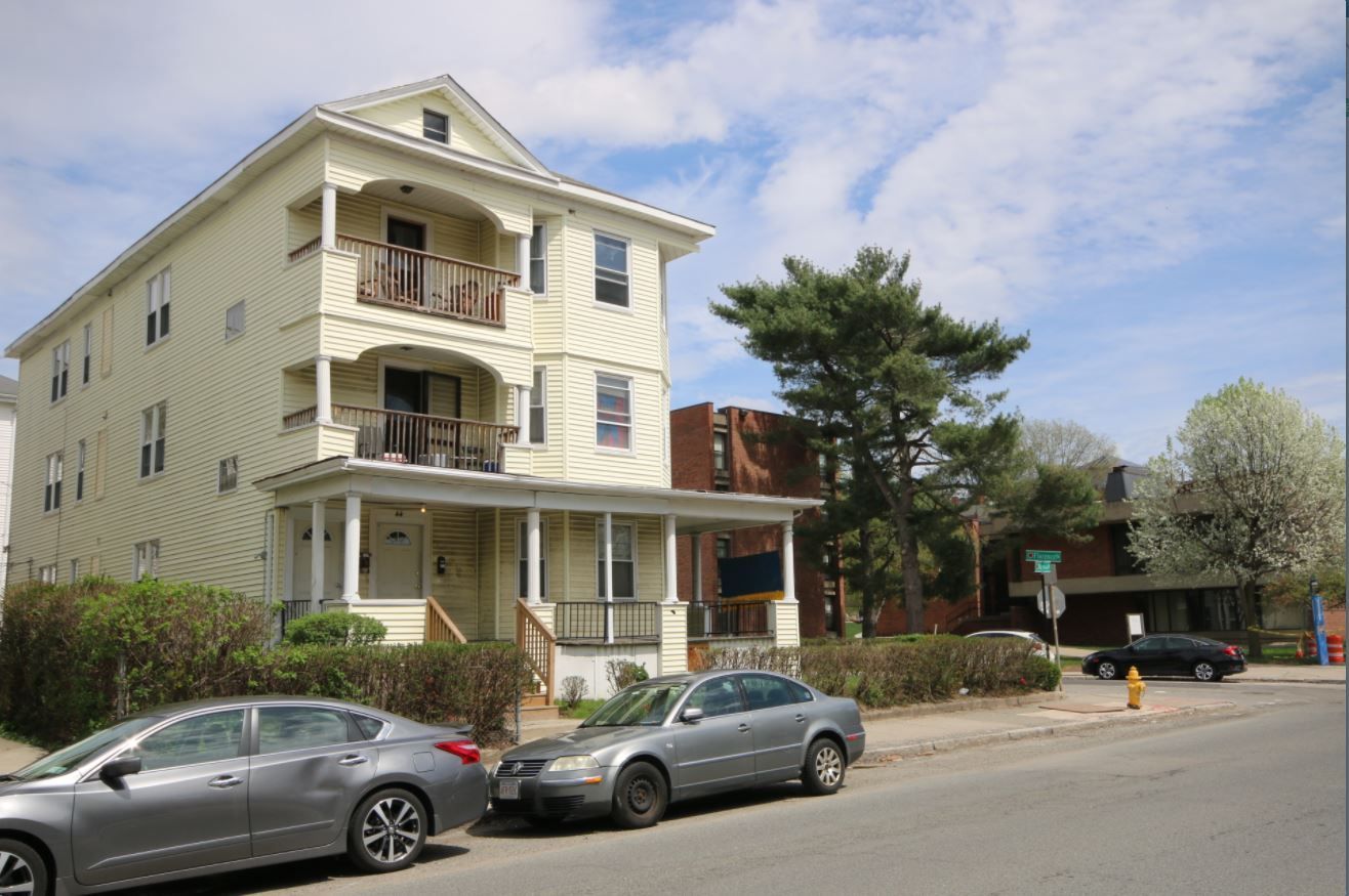A row of cars are parked in front of a building