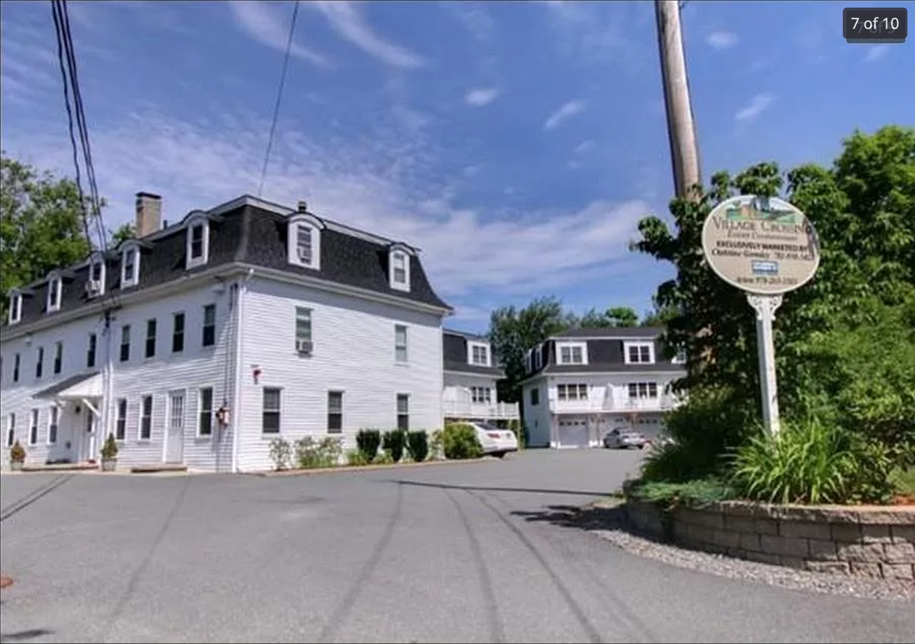 A white house with a sign in front of it that says ' house on the hill '