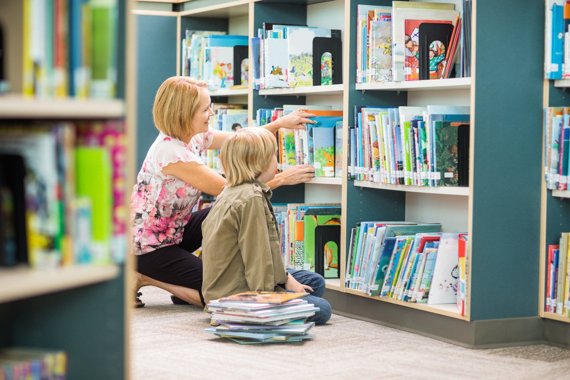 Librarian and child searching book shelves