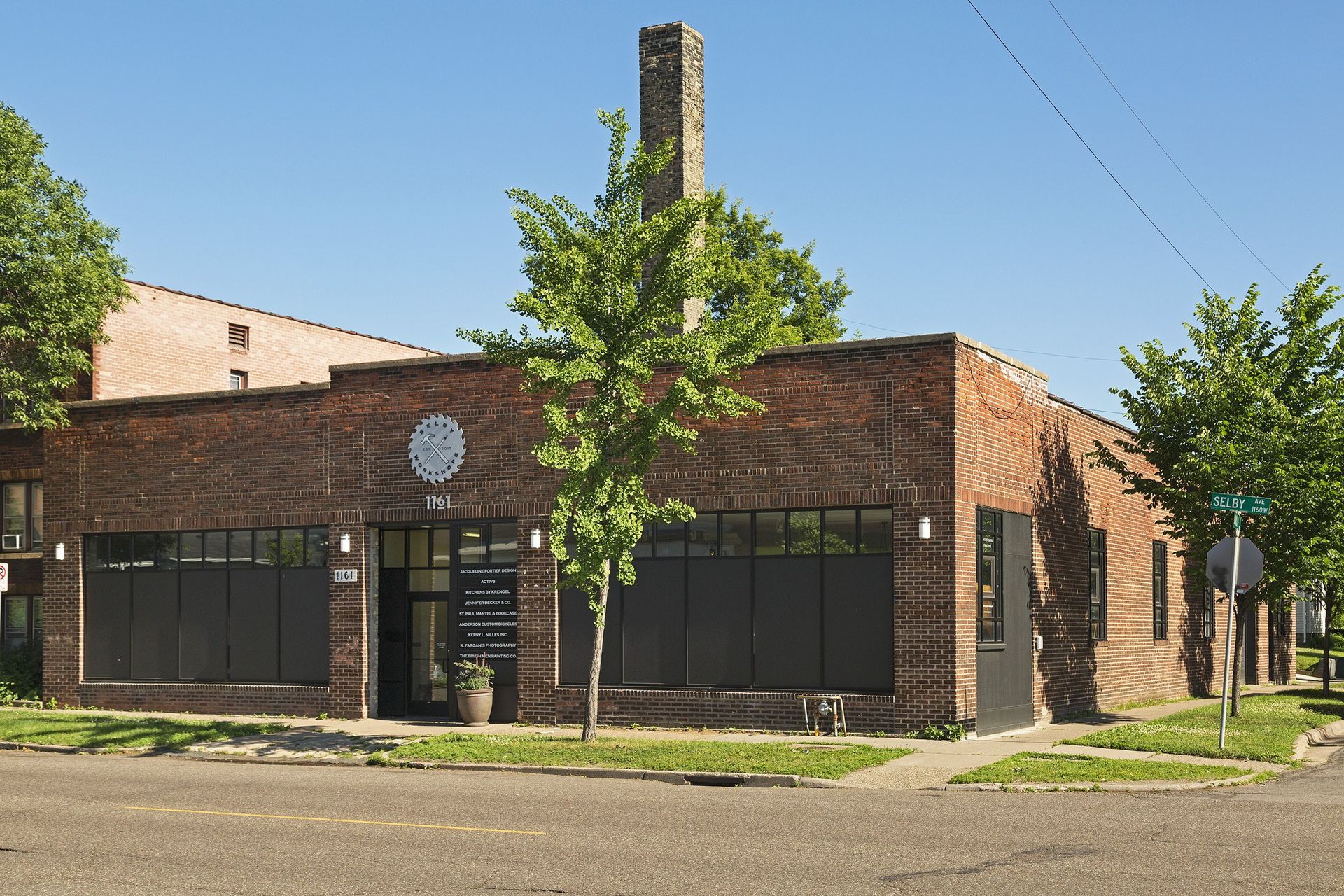 Red brick apartment building with rectangular windows against a blue sky with clouds.