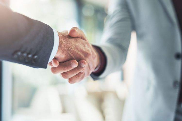 Close-up of two people shaking hands in a bright office setting