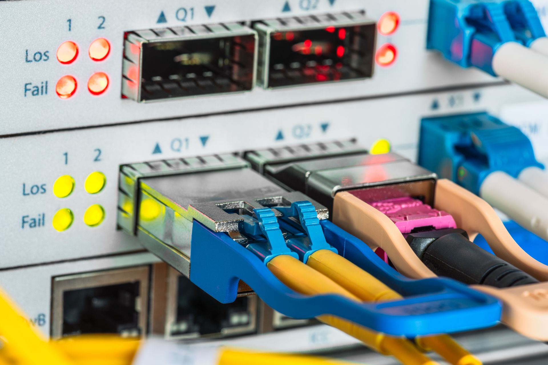 Ethernet cables plugged into network switches with colored status lights in a server rack.