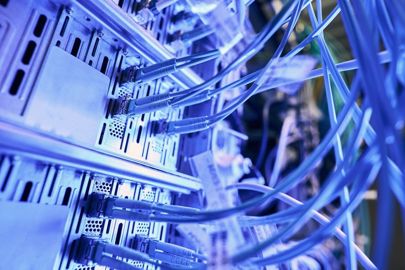 Blue-lit network server rack with bundled Ethernet cables connected to switch ports