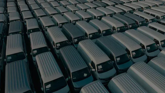 Fileiras de ônibus ou vans pretas estacionadas em um terreno, vistas de cima.