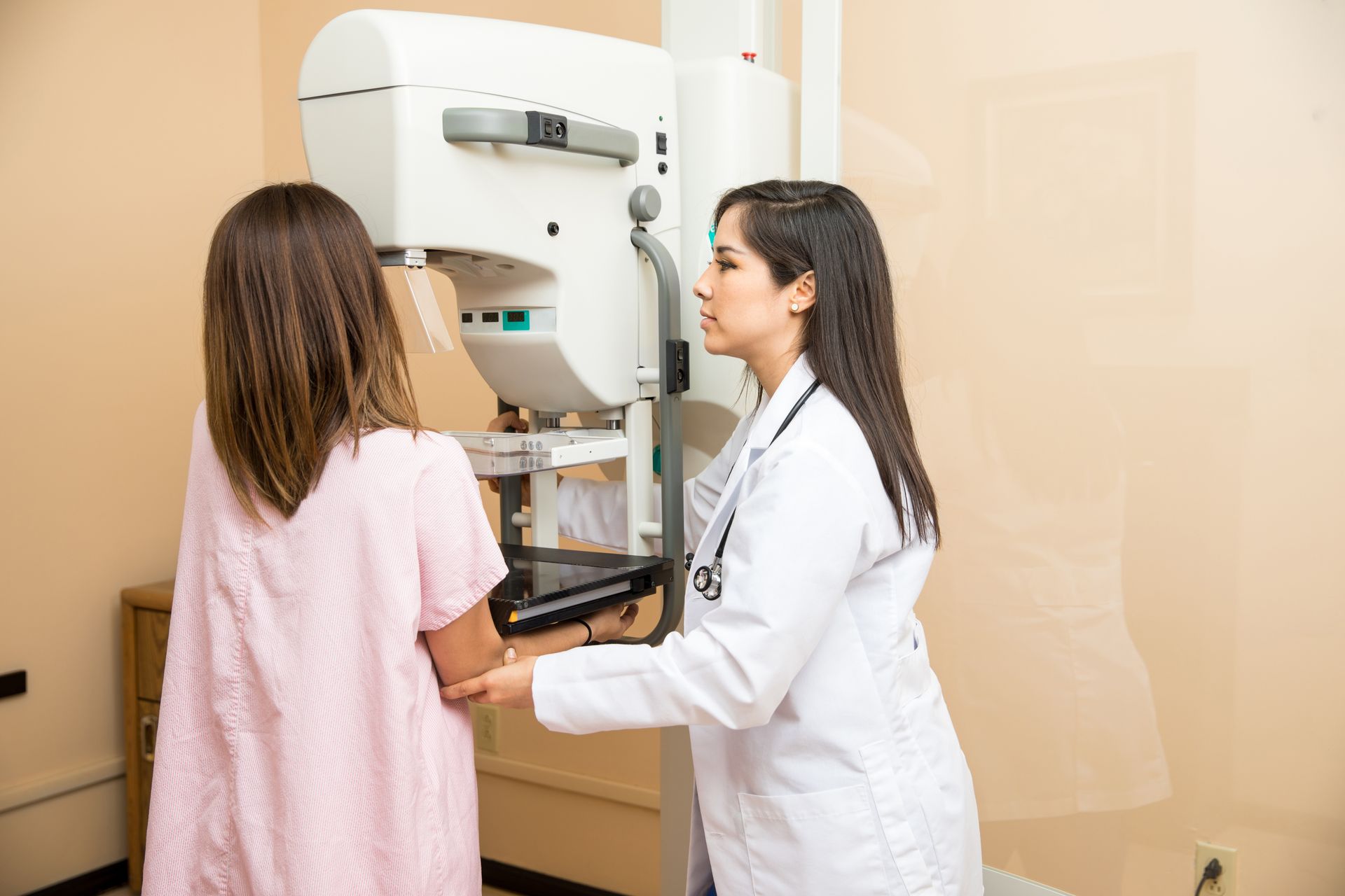 Doctor helping patient get a mammogram in a hospital.