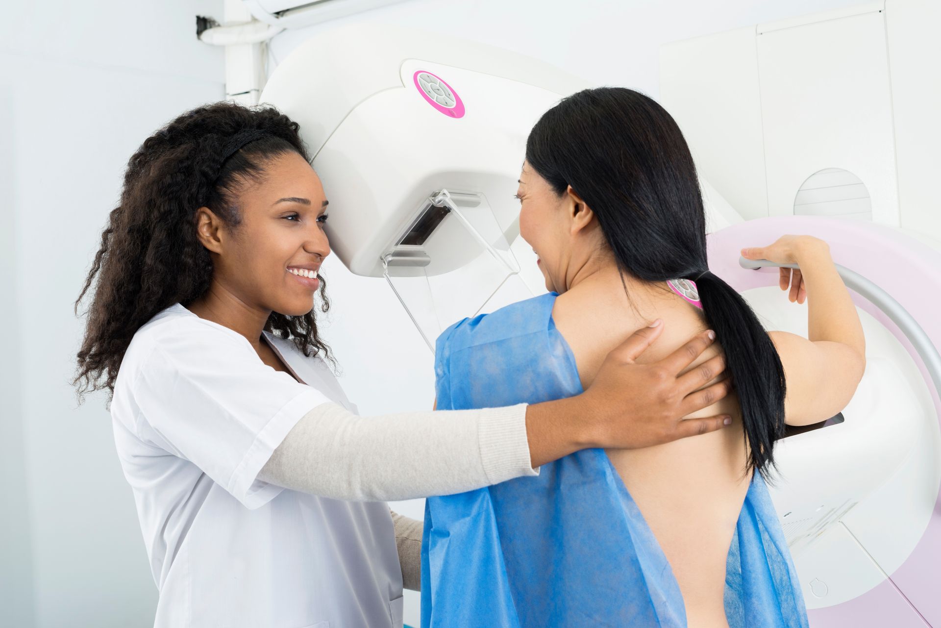 Happy doctor assisting woman undergoing mammogram x-ray test. Happy doctor assisting woman undergoing mammogram x-ray test.