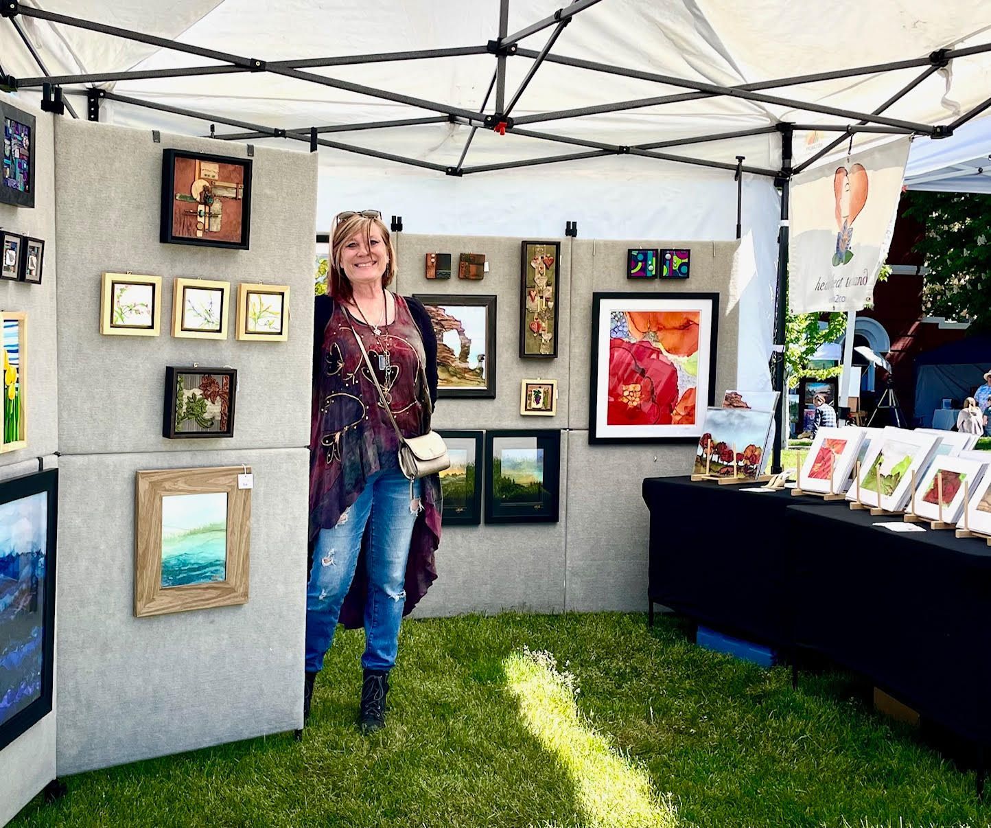 A woman is standing in front of a wall with paintings on it.