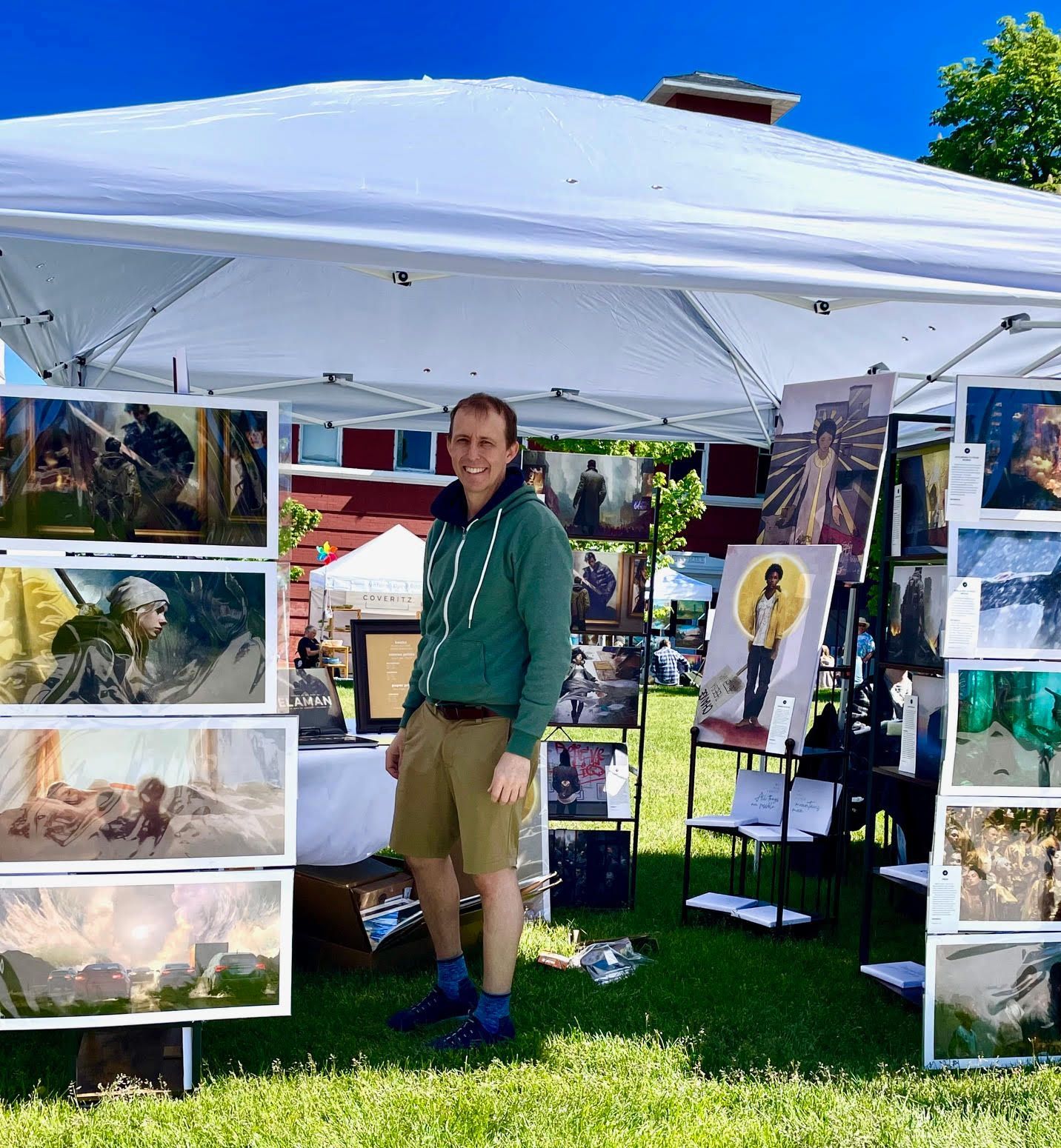 A man is standing in front of a tent with pictures on it