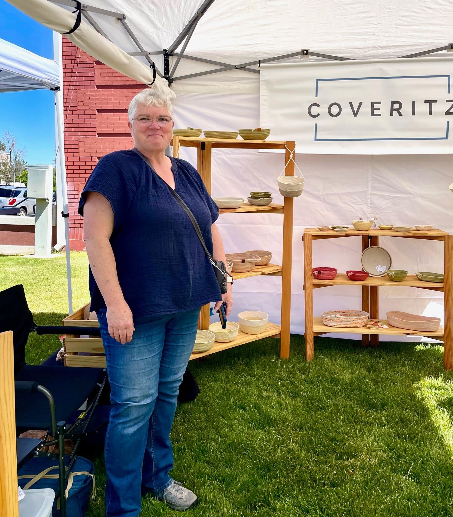 A woman is standing in front of a tent with a sign that says coveritz