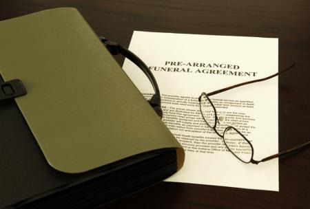 Legal agreement document beside eyeglasses and a black binder on a table.