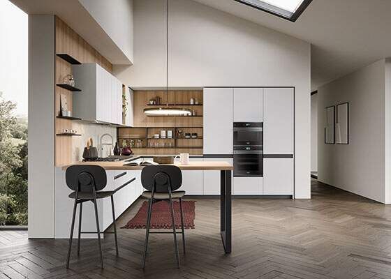 Cucina moderna con mobili bianchi, dettagli in legno, isola e lucernario.