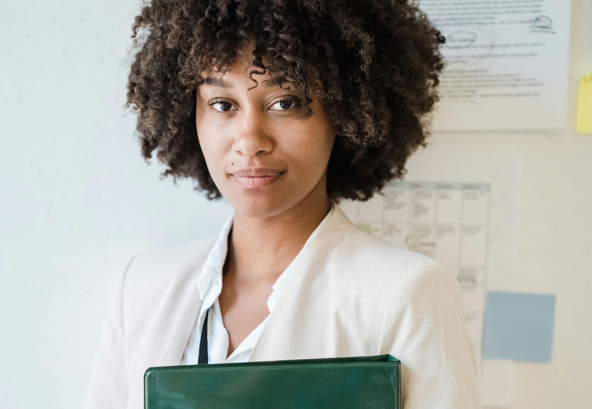 A woman with curly hair is holding a green briefcase.