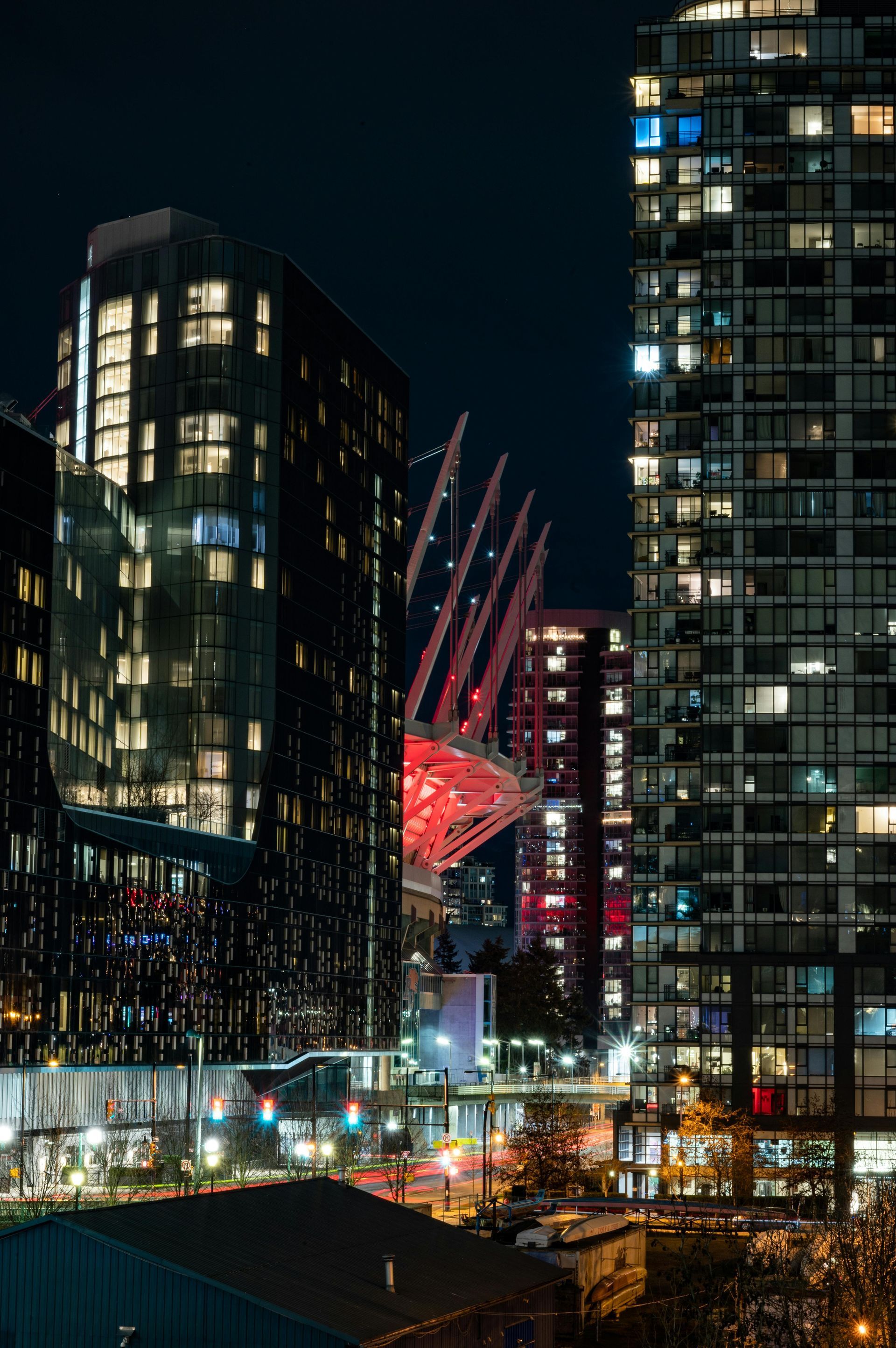 A city at night with a lot of tall buildings and a red building in the middle.