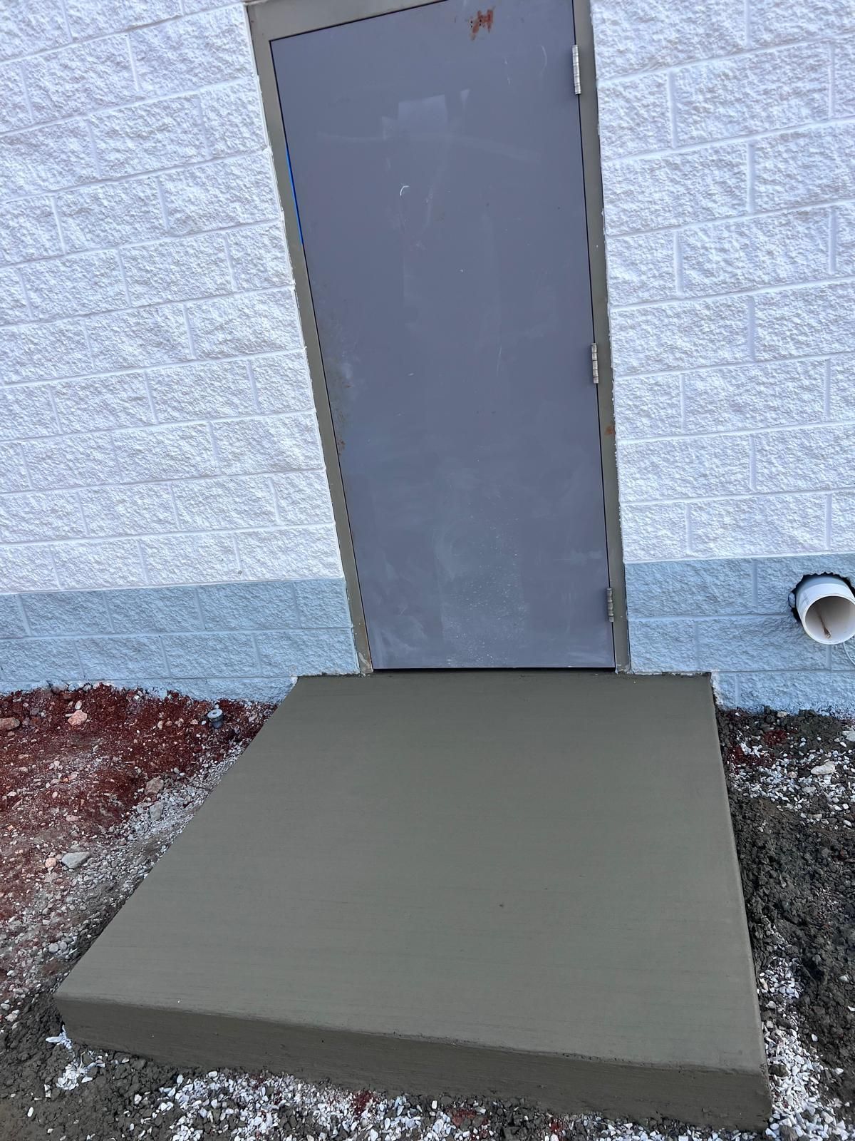 Concrete ramp leading to a gray door on a light blue exterior wall.