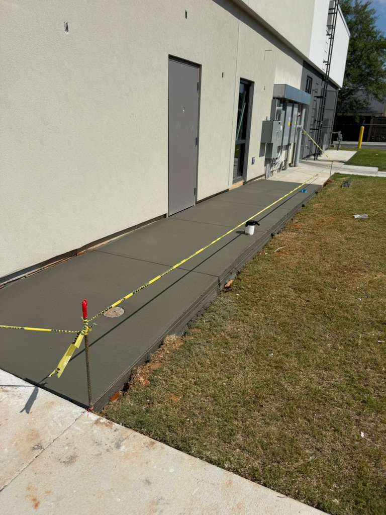 Ramped walkway beside a building, marked with yellow caution tape and cones under construction.