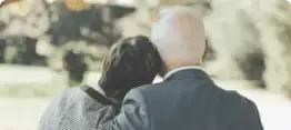 Two people walking closely outdoors, one resting their head on the other’s shoulder