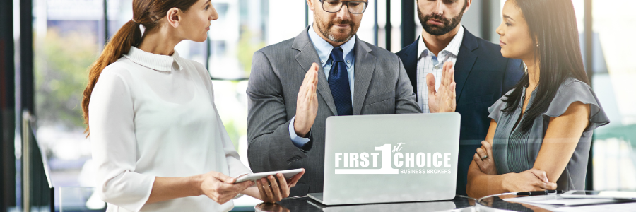 A group of business people are standing around a laptop computer.