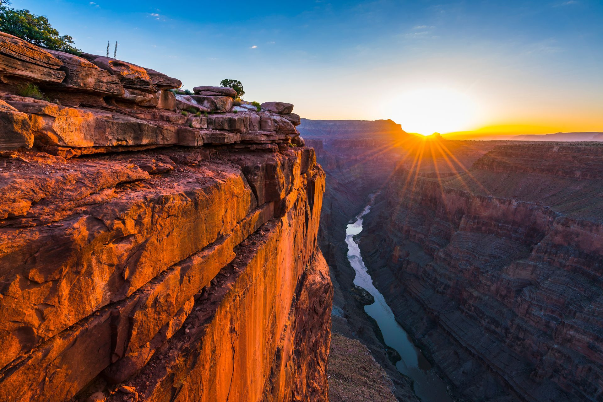 Hiker descending stone steps overlooking a vast canyon under a clear blue sky