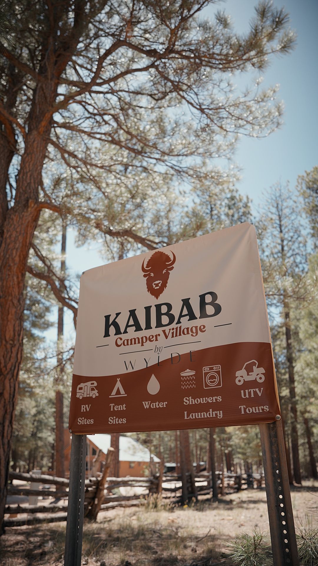 Kaibab campground sign in a wooded area with tall trees and a blue sky