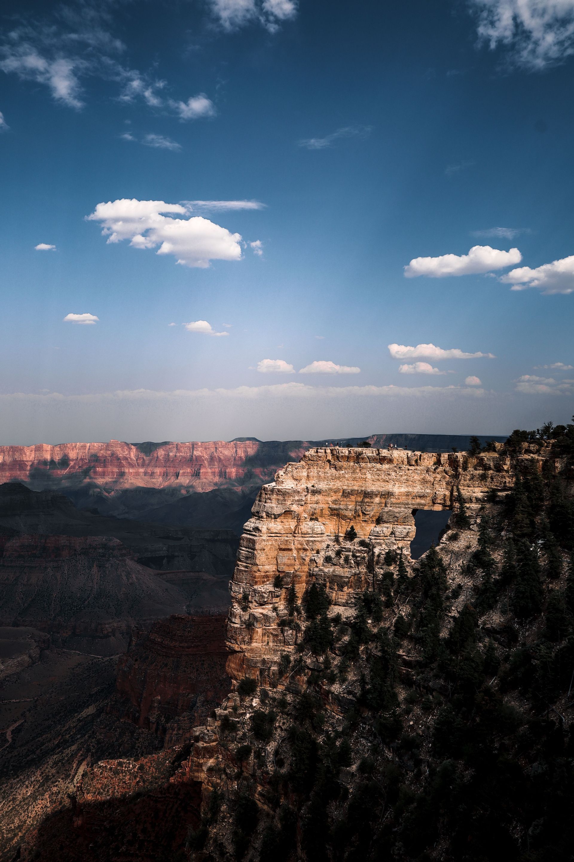 Grand Canyon cliffs under a blue sky with scattered clouds at sunset