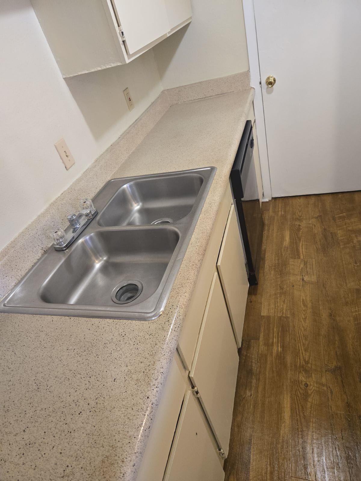 A kitchen with a stainless steel sink and white cabinets