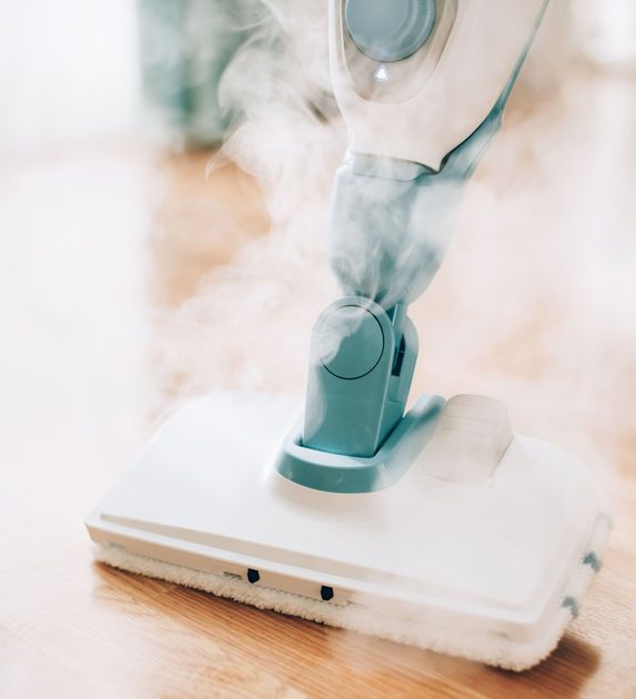 Cordless vacuum cleaner steaming a white floor on a wooden surface